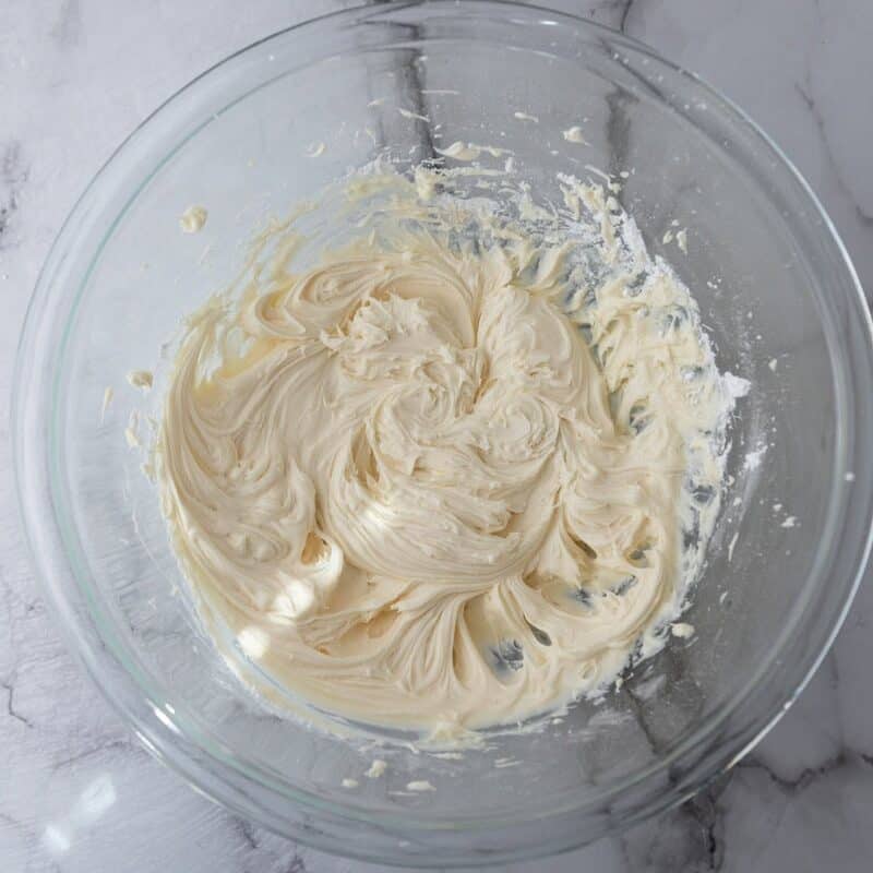 Frosting mixture in a glass bowl after combining the powdered sugar and vanilla extract