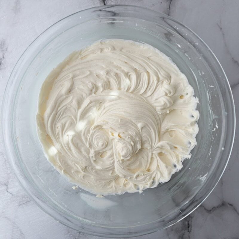 Finished mascarpone frosting in a glass bowl whipped to a smooth, fluffy consistency