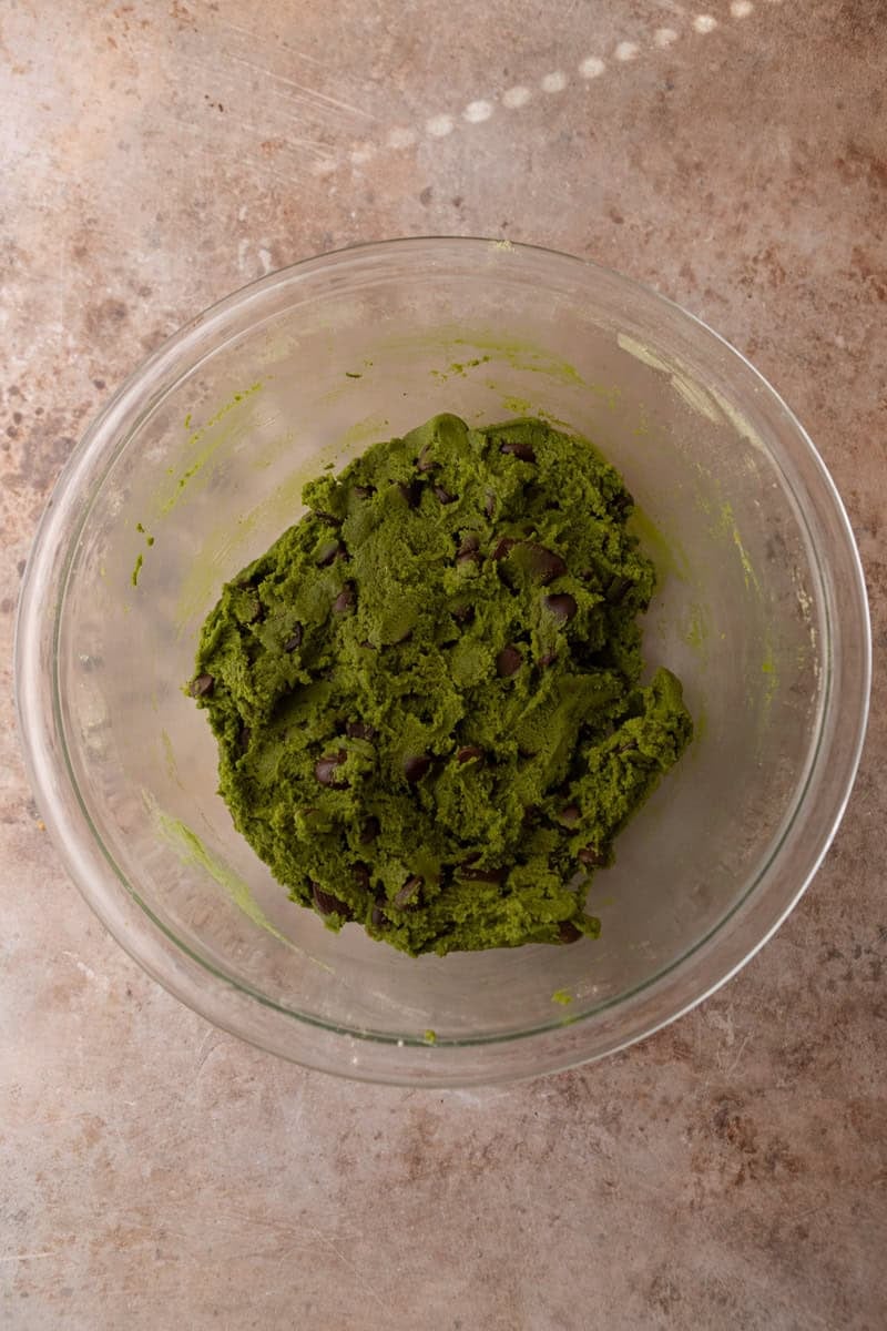 Finished matcha cookie dough with chocolate chips mixed throughout in a glass bowl