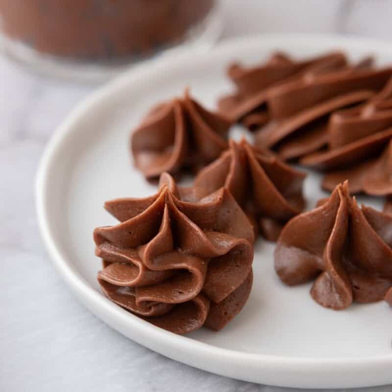 chocolate buttercream piped into rosettes on a white plate