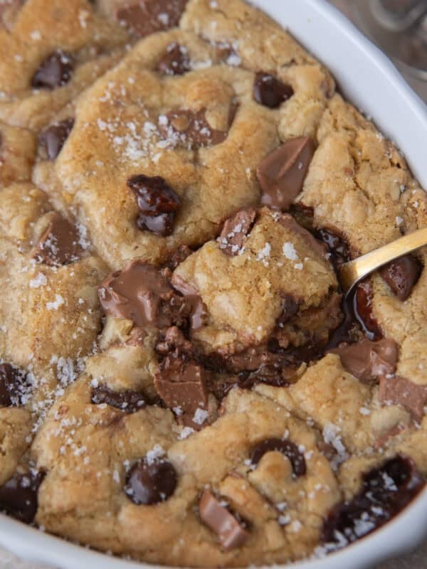 Scoopable chocolate chip cookie with molten chocolate center being scooped from a baking dish