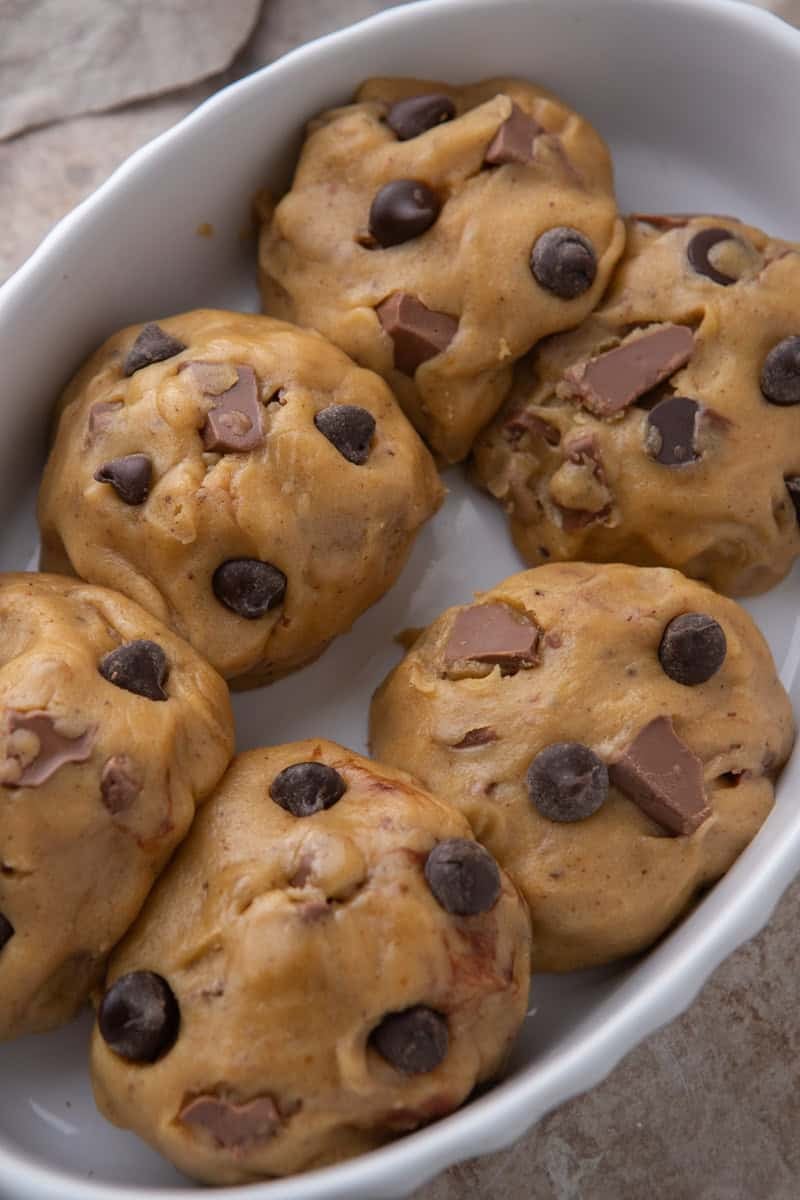 Chocolate chip cookie dough balls arranged in a baking dish before baking