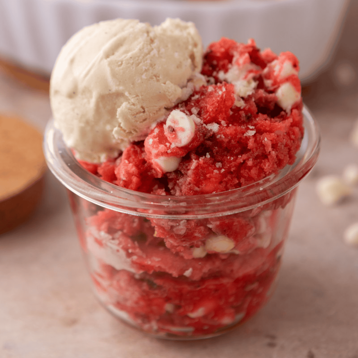 Strawberry scoopable cookie served in a glass jar with a scoop of vanilla ice cream on top