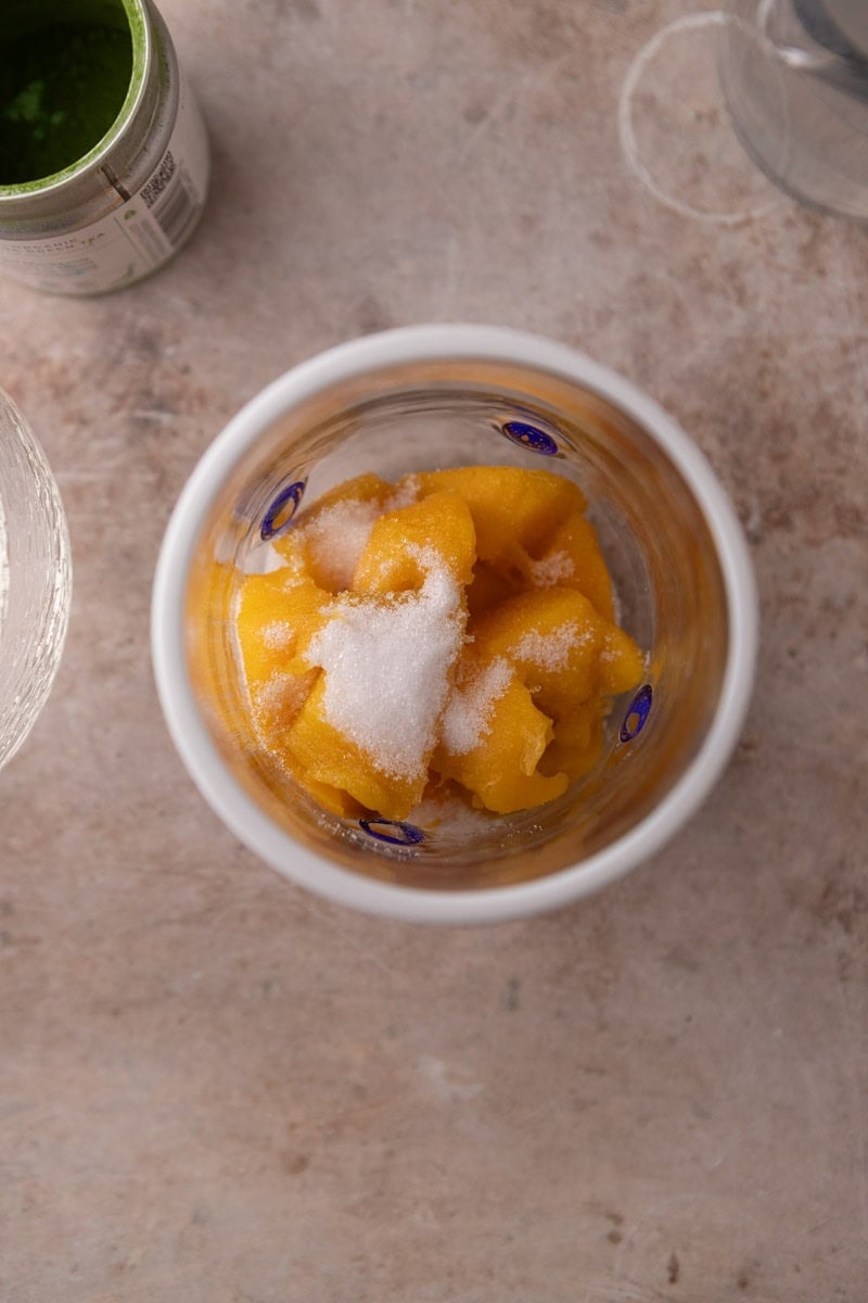 fresh mango chunks and sweetener in a wide mouth glass before blending