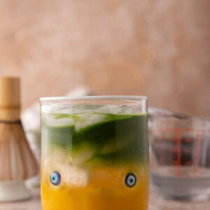 iced mango matcha drink with coconut water in a glass with golden mango and green matcha layers