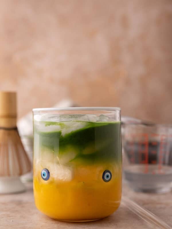 iced mango matcha drink with coconut water in a glass with golden mango and green matcha layers