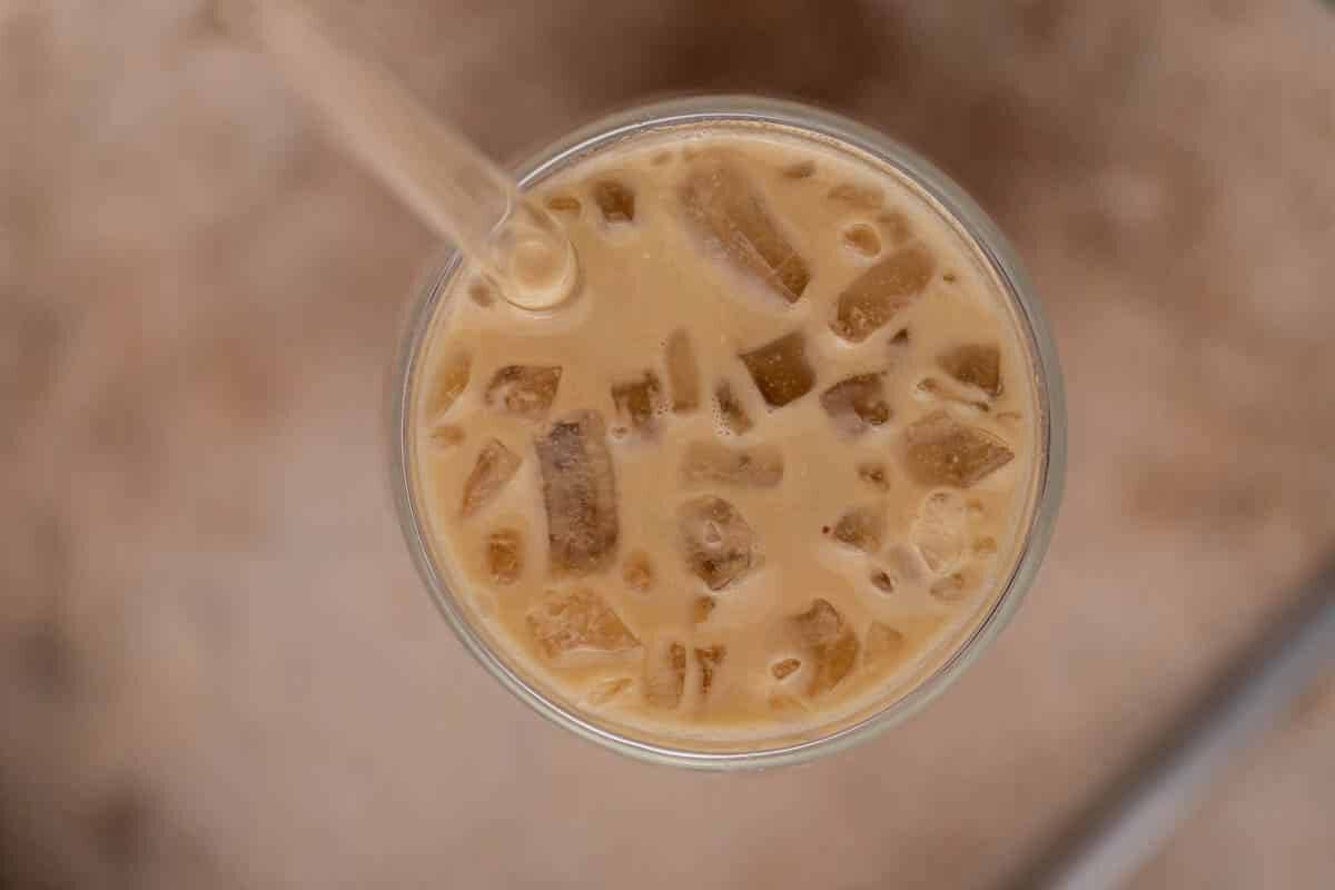 Overhead view of a cold caramel coffee with ice cubes and a straw