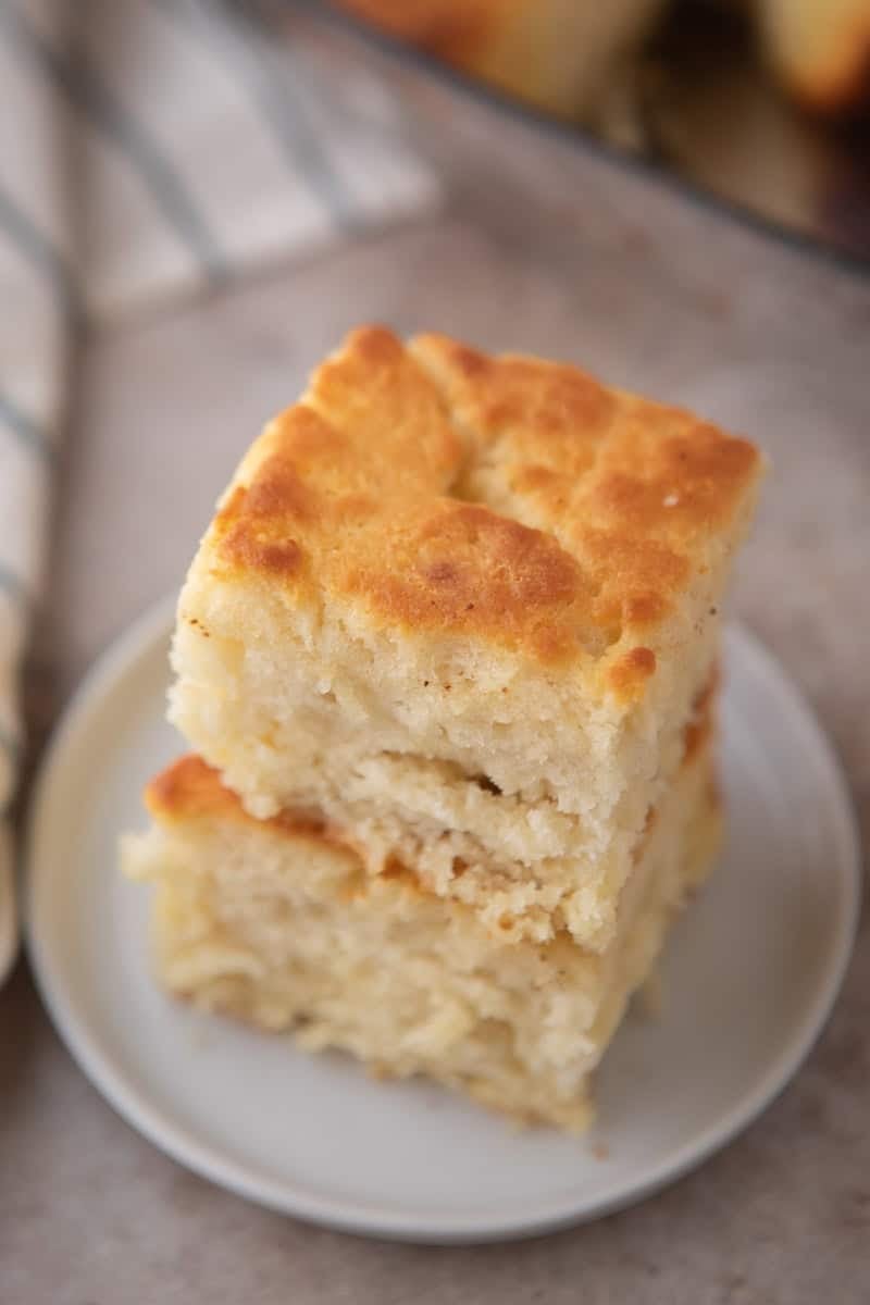 Two butter swim biscuits stacked on a small white plate photographed from a slight overhead angle showing the golden brown tops and soft tender interior crumb.