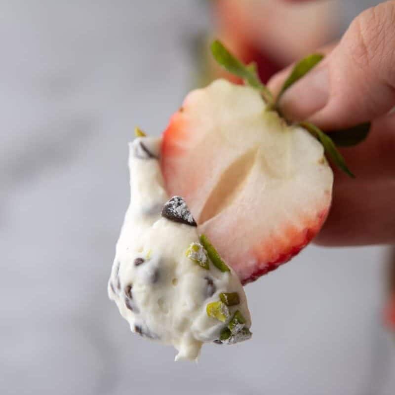 A strawberry dipped into a bowl of fluffy cannoli cream. The thick, scoop-able dip clings perfectly for easy scooping and snacking.