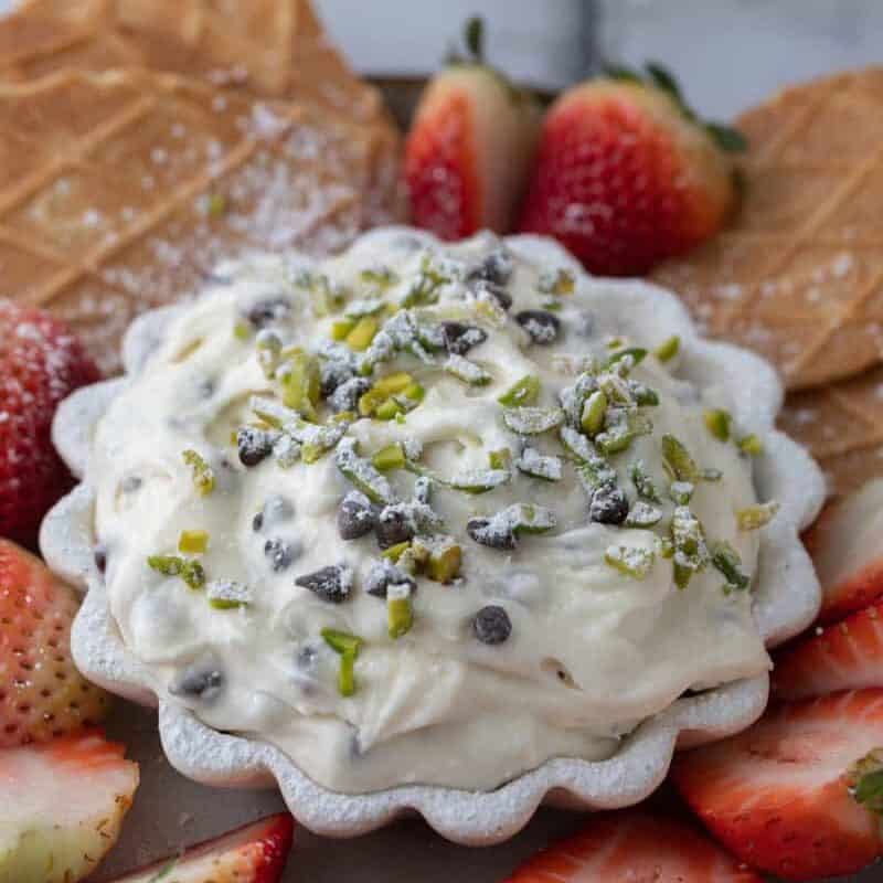 Cannoli dip served with an assortment of dippers including pizzelle cookies, strawberries, pretzels and waffle cones. The sweet dip pairs perfectly with a variety of crunchy and fruity options.