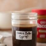 Homemade cookie butter coffee syrup in a labeled mason jar with a jar of Lotus Biscoff cookie butter in the background.