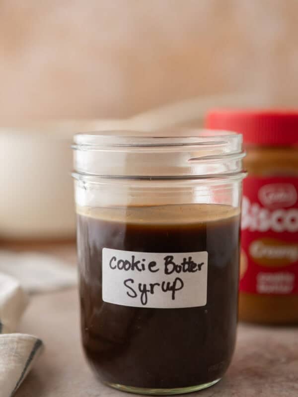 Homemade cookie butter coffee syrup in a labeled mason jar with a jar of Lotus Biscoff cookie butter in the background.