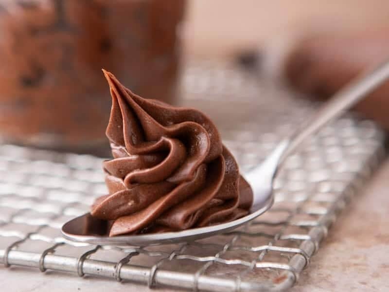 Chocolate cream cheese frosting swirled on a spoon showing the fudgy, silky texture