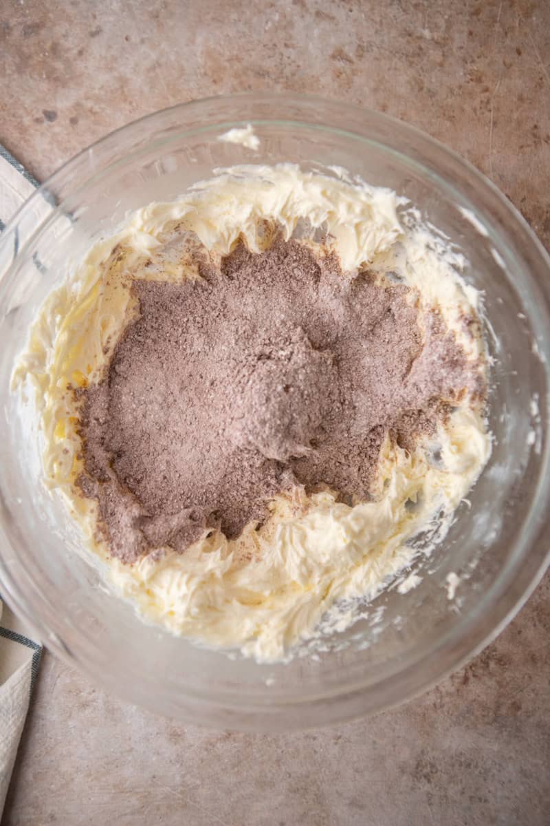 Sifted cocoa powder and powdered sugar added to beaten cream cheese and butter in a glass bowl