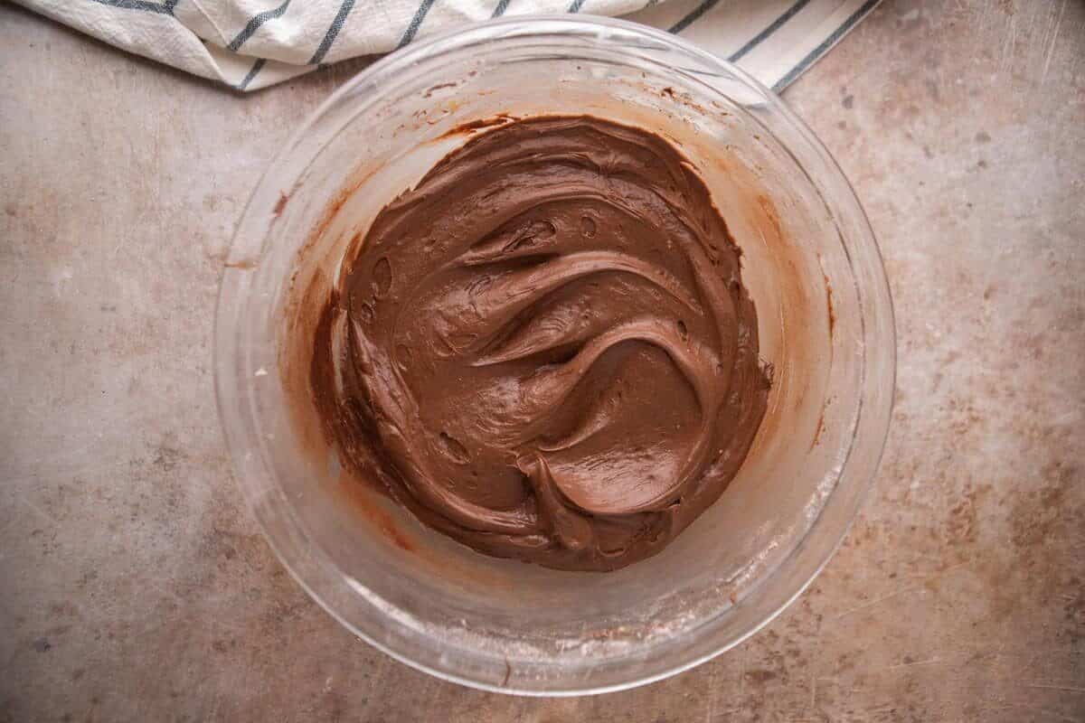 Smooth and creamy chocolate cream cheese frosting in a glass mixing bowl