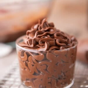 Chocolate cream cheese frosting piped into a glass jar showing smooth, glossy swirls