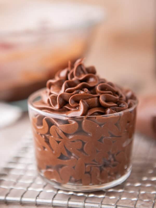 Chocolate cream cheese frosting piped into a glass jar showing smooth, glossy swirls