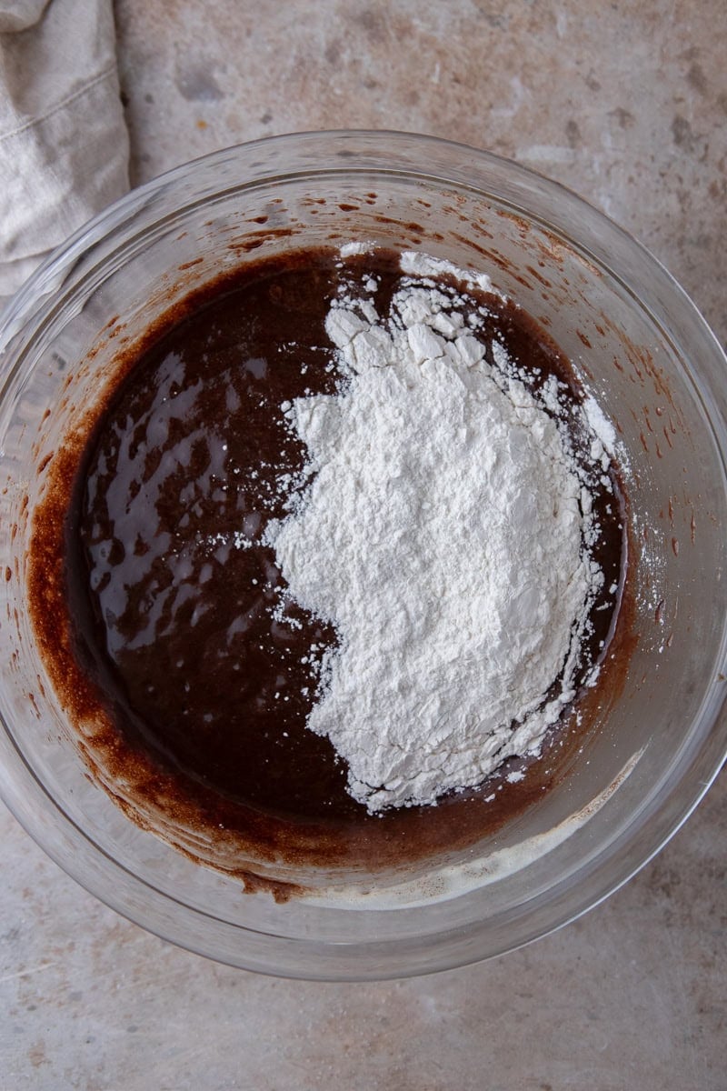 Brownie batter with flour and cornstarch sifted on top before folding