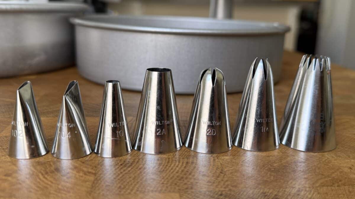 Piping tips lined up on the counter to show which ones were used in decorating this cake