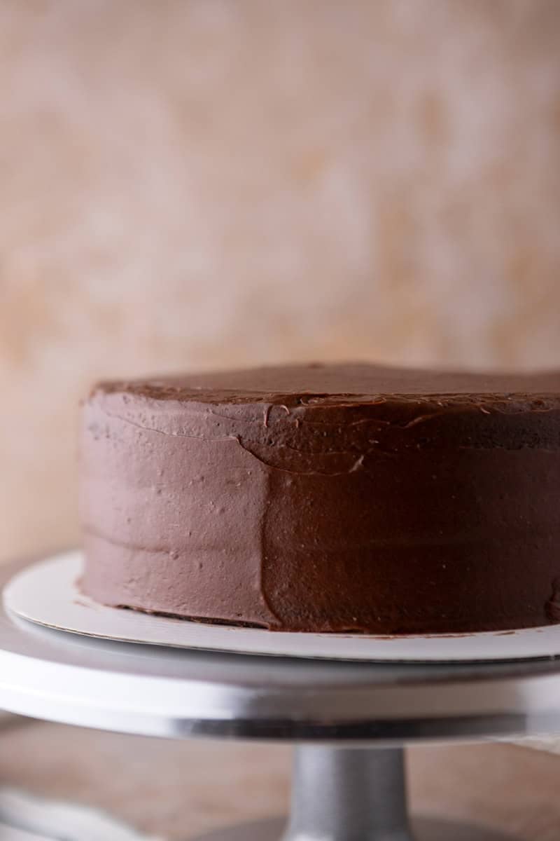 Layered marble cake with a crumb coat of chocolate cream cheese frosting on a cake turntable