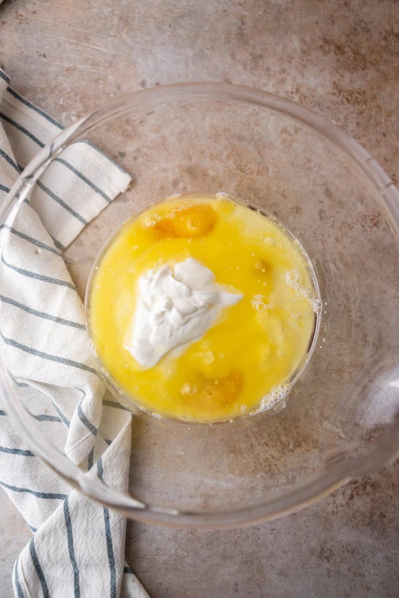 Eggs, melted butter, sour cream, and oil combined in a glass mixing bowl