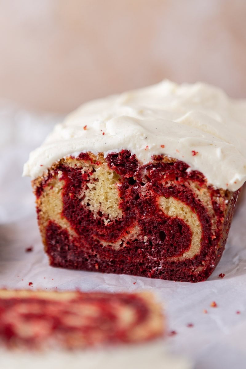 Straight view of a frosted marbled red velvet cake with thick cream cheese frosting on top, showing all the different layers of marbling