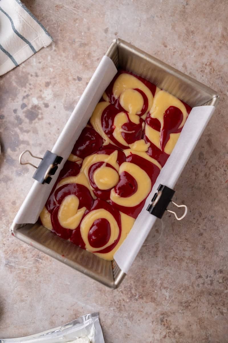 Overhead shot of marbled cake batter in a loaf pan before swirling a knife through it.