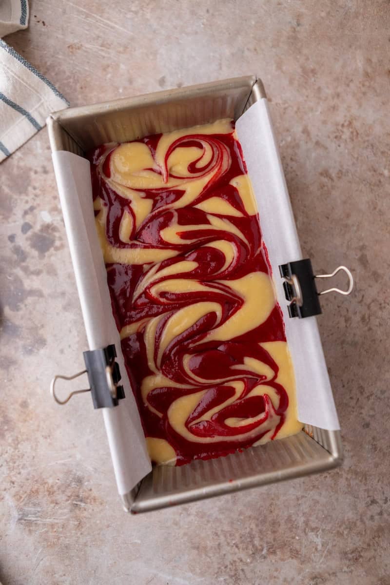 Overhead shot of marbled cake batter in a loaf pan after swirling it a sharp knife.