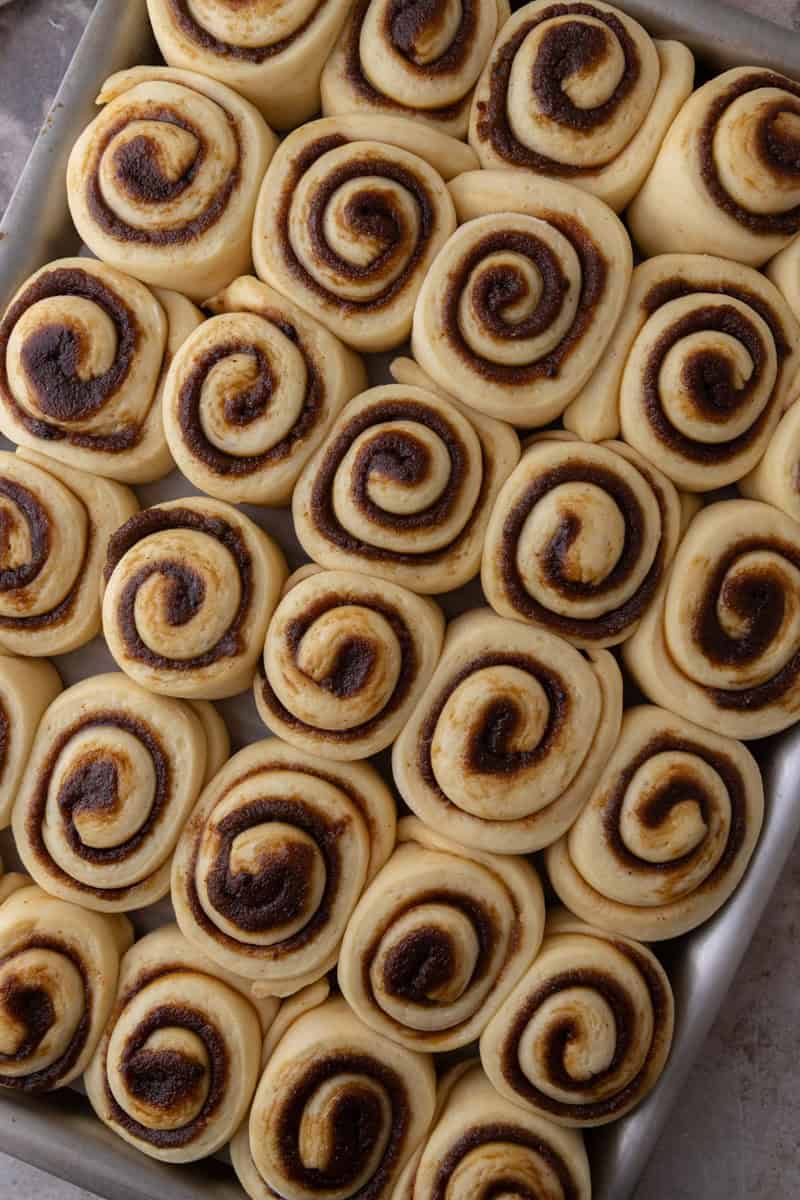 Mini cinnamon rolls after proofing in a sheet pan, puffy and touching