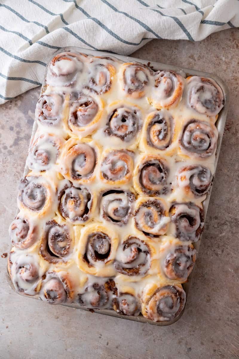 Mini cinnamon rolls with thin cream cheese glaze drizzled over the top in a sheet pan