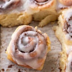Single mini cinnamon roll with cream cheese glaze pulled from the pan showing soft texture