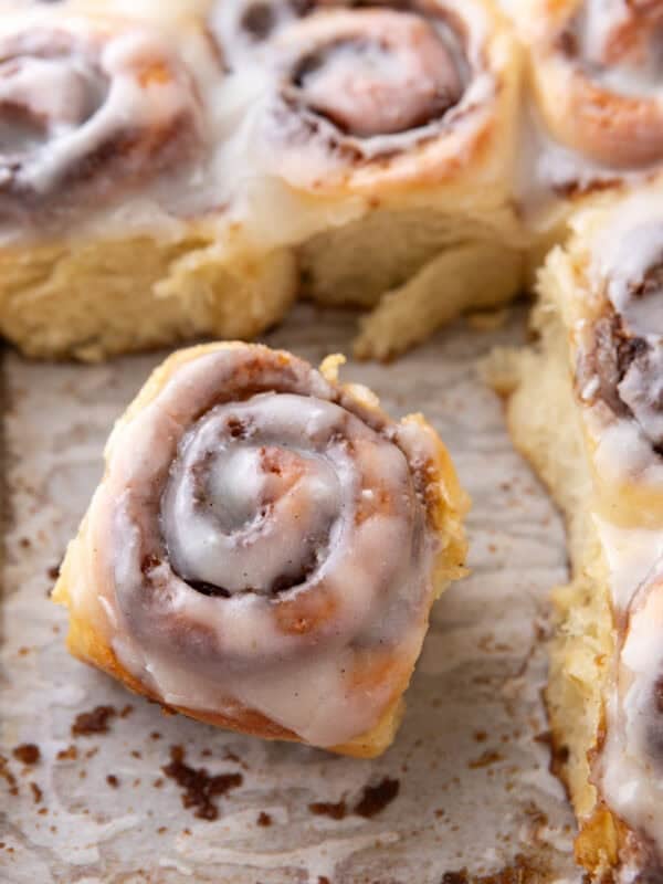 Single mini cinnamon roll with cream cheese glaze pulled from the pan showing soft texture