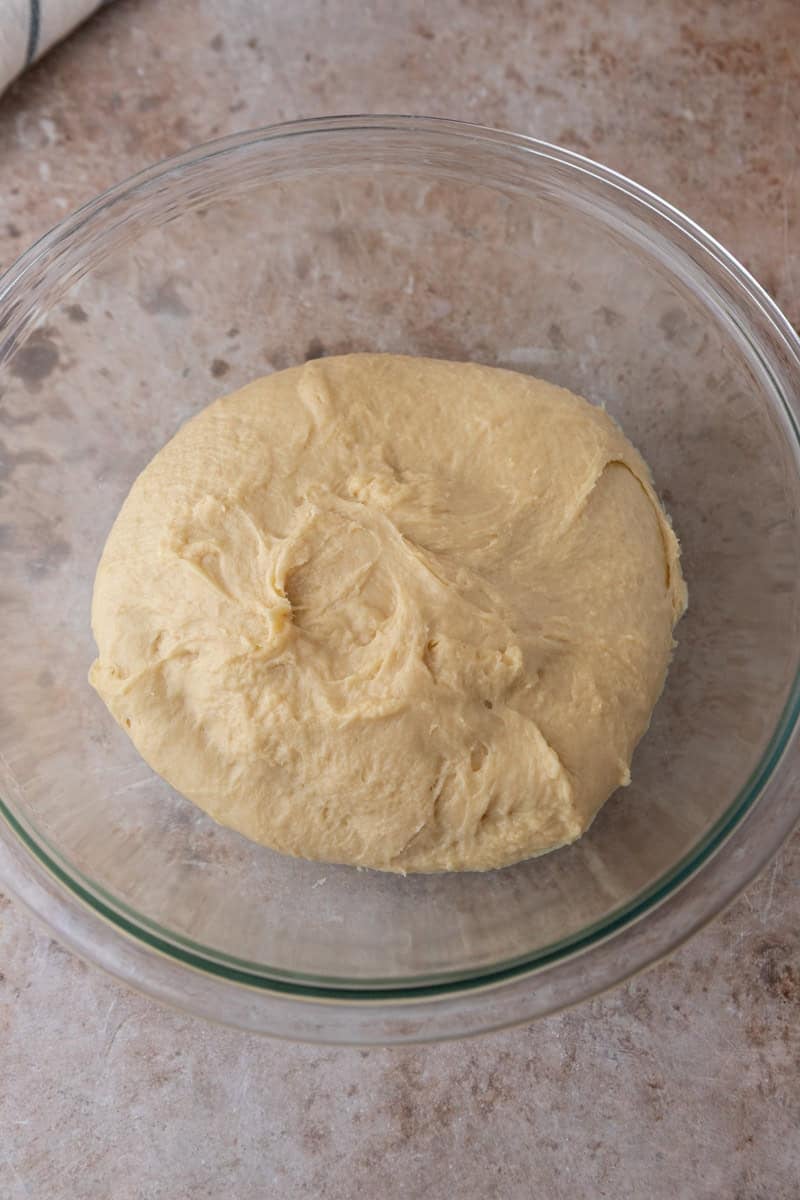 Smooth brioche style cinnamon roll dough in a glass bowl after kneading