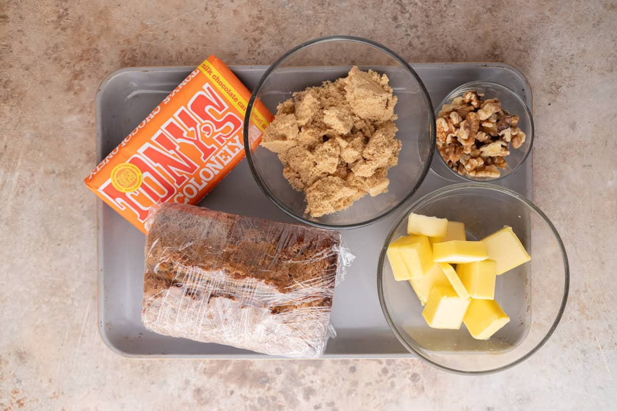 Ingredients for banana bread Christmas crack including Tony's Chocolonely, brown sugar, butter, walnuts, and banana bread.