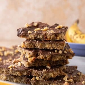Stack of banana bread Christmas crack pieces on a plate with a banana in the background.