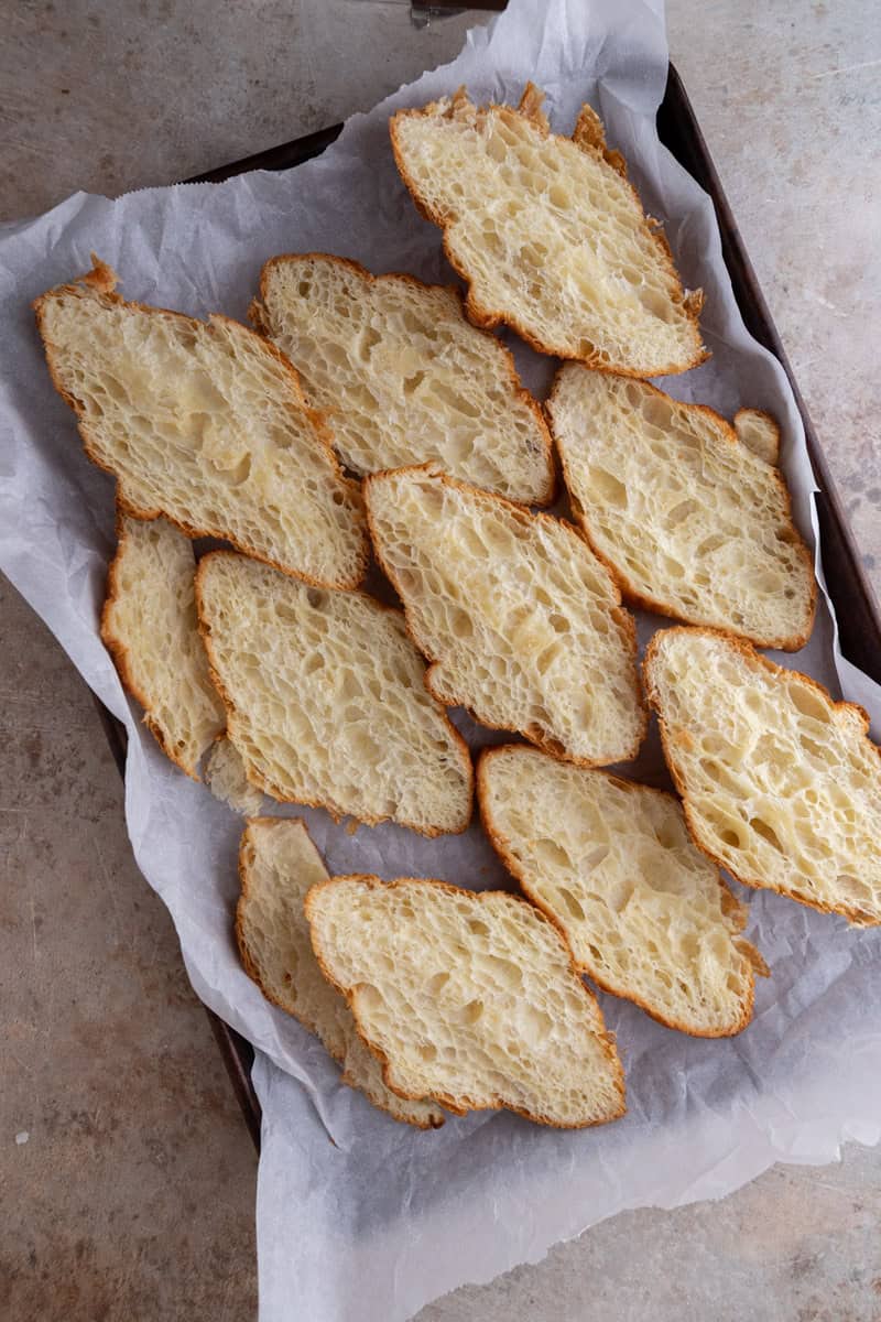 Day-old croissants sliced lengthwise and laid cut side down on a parchment-lined baking sheet
