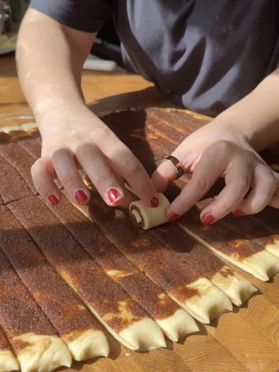 Hand rolling mini cinnamon rolls from the center