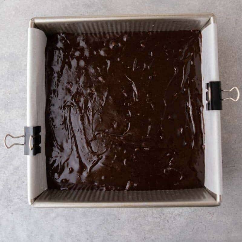 brownie batter spread over graham crackers in a parchment-lined pan