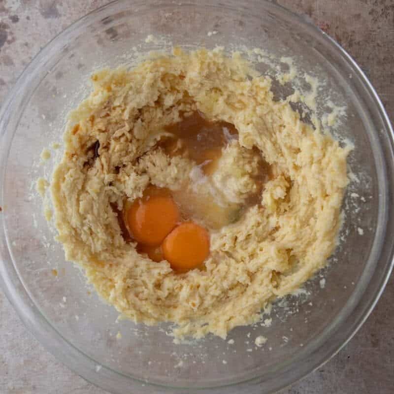 Eggs and lemon juice added to creamed butter and sugar in a glass bowl for lemon cookie dough.