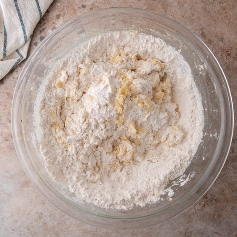 Dry ingredients added to lemon cookie dough in a glass bowl before mixing