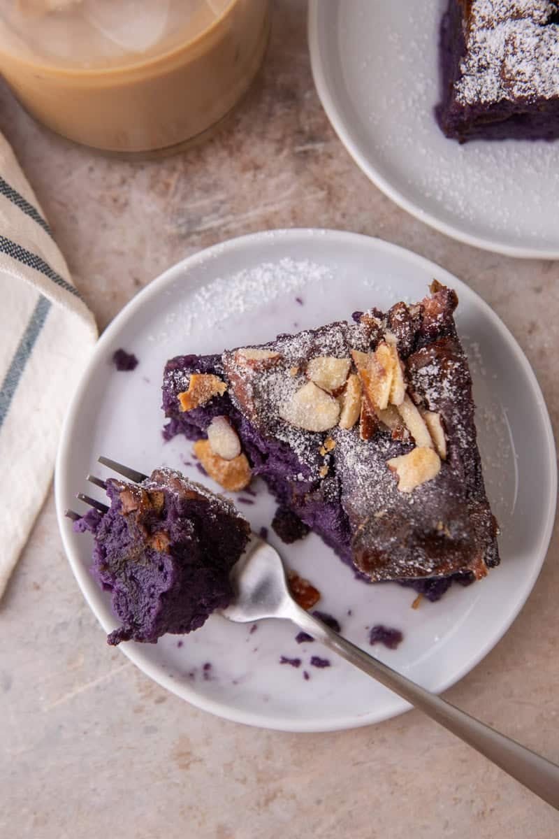 Overhead view of a slice of ube French toast bake on a white plate with a forkful pulled out