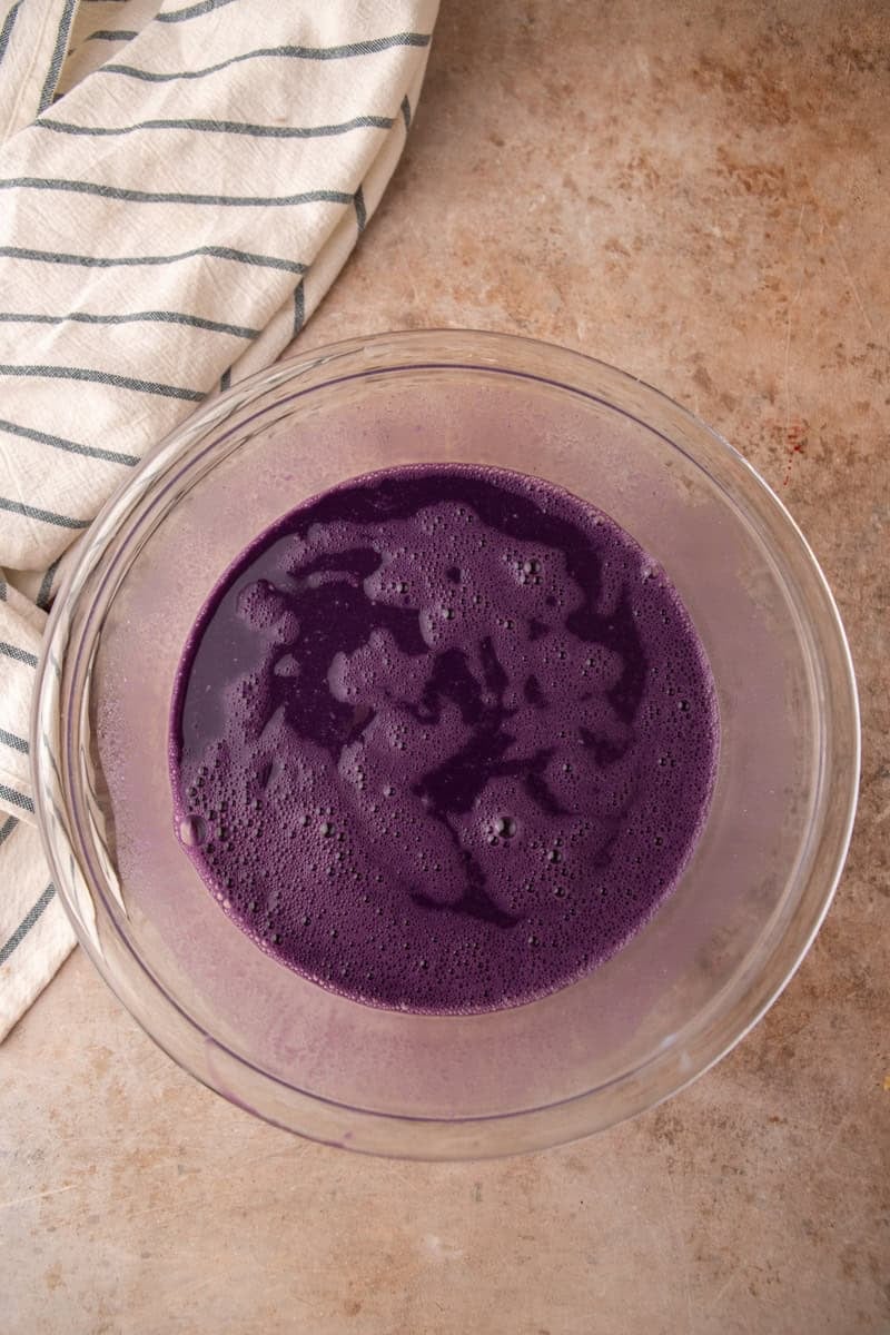 Vibrant purple coconut milk and ube custard whisked smooth in a glass bowl