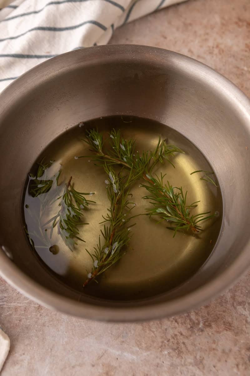 Finished rosemary simple syrup with steeped sprigs in a saucepan