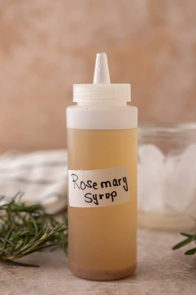 Homemade rosemary syrup in a squeeze bottle with a handwritten label