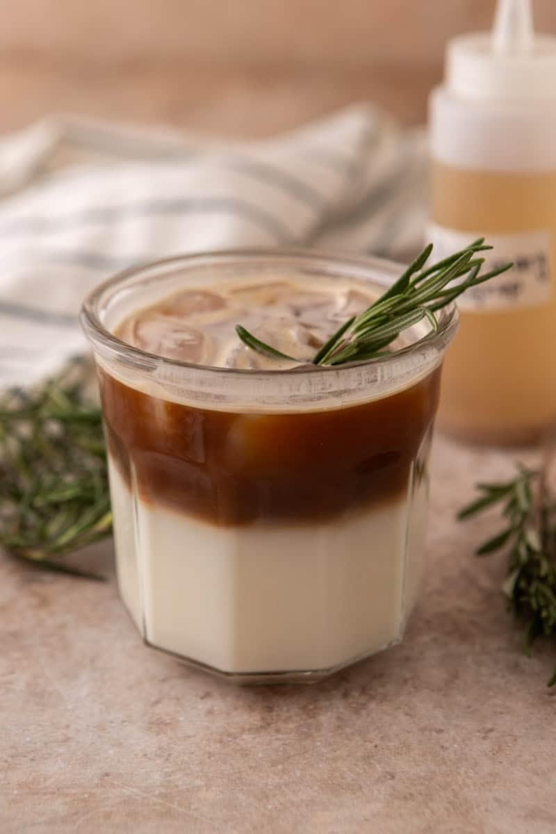 Layered rosemary latte with milk on the bottom and espresso poured over ice on top
