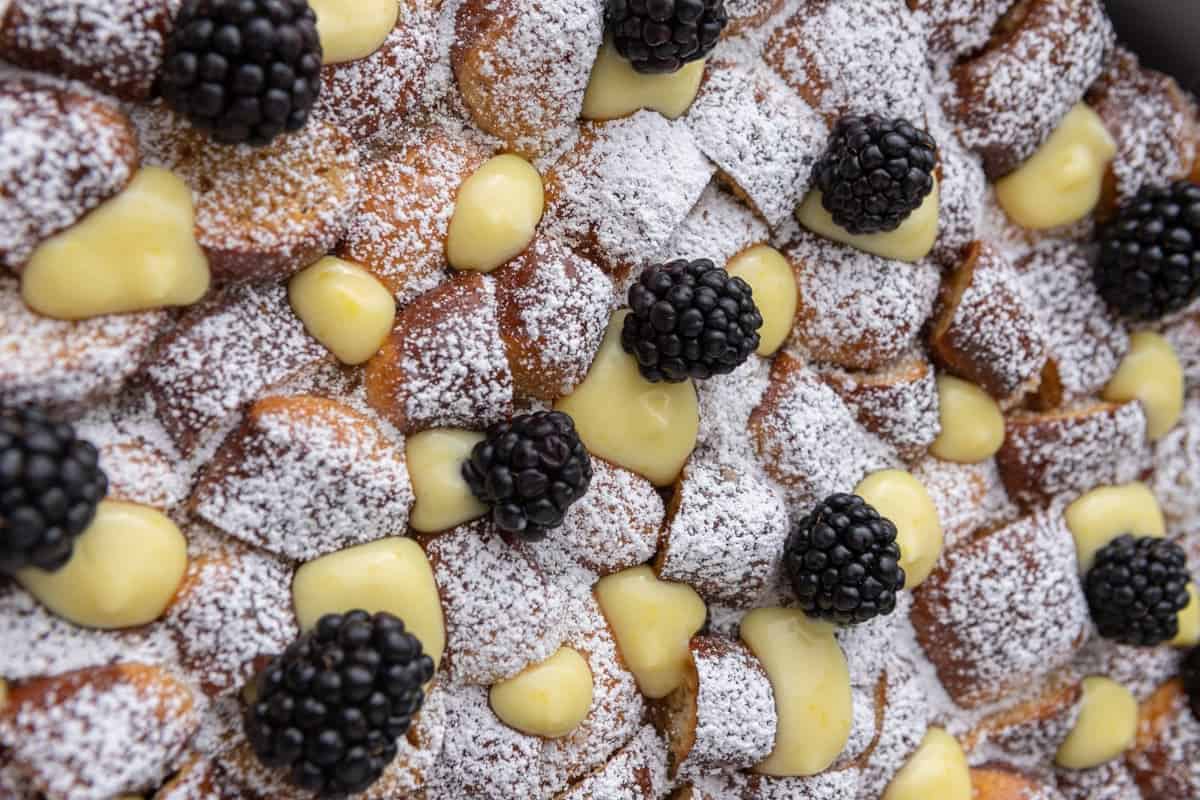 Easy Mother's Day brunch recipe with pretzel French toast bake topped with lemon curd, fresh blackberries, and powdered sugar