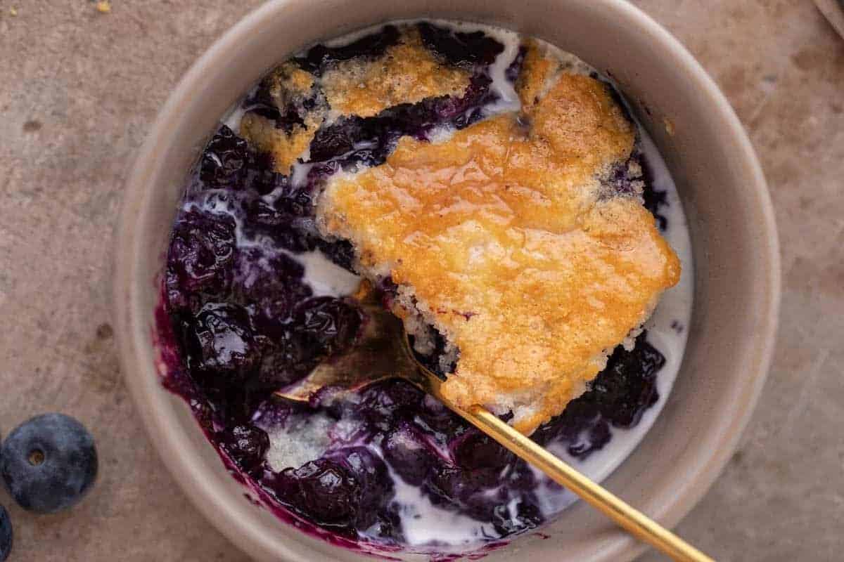 Close up of easy blueberry cobbler served in a bowl with vanilla ice cream