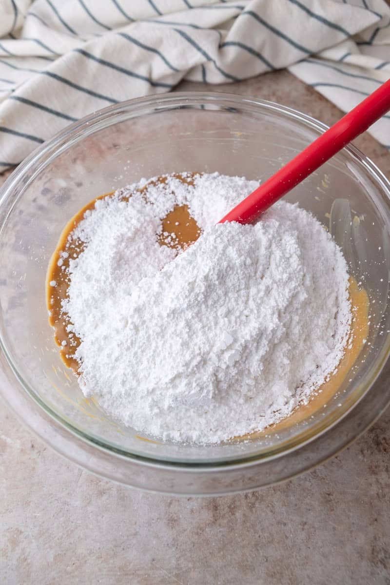 Powdered sugar added to the peanut butter mixture in a glass bowl