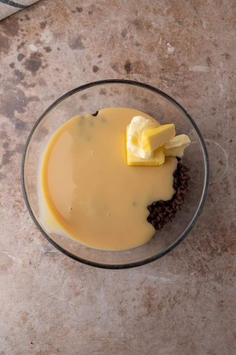 Chocolate chips, sweetened condensed milk, and butter in a glass bowl before melting