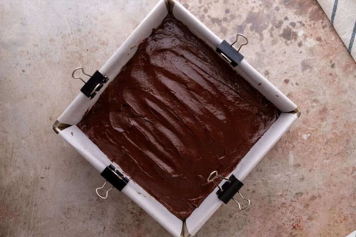 Melted chocolate spread over the peanut butter layer in a parchment lined pan